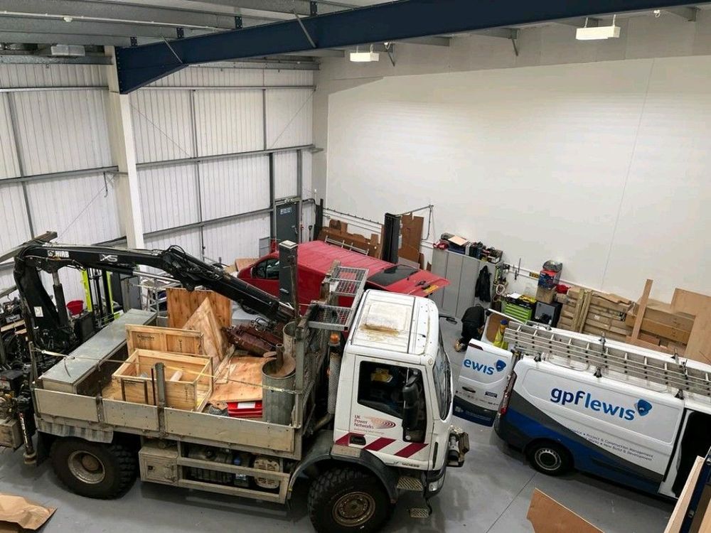 A tipper truck in the workshop next to stacked racking